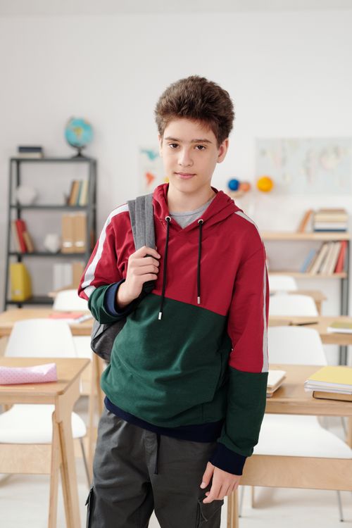 Free A teenage student with a backpack standing in a bright classroom setting. Stock Photo