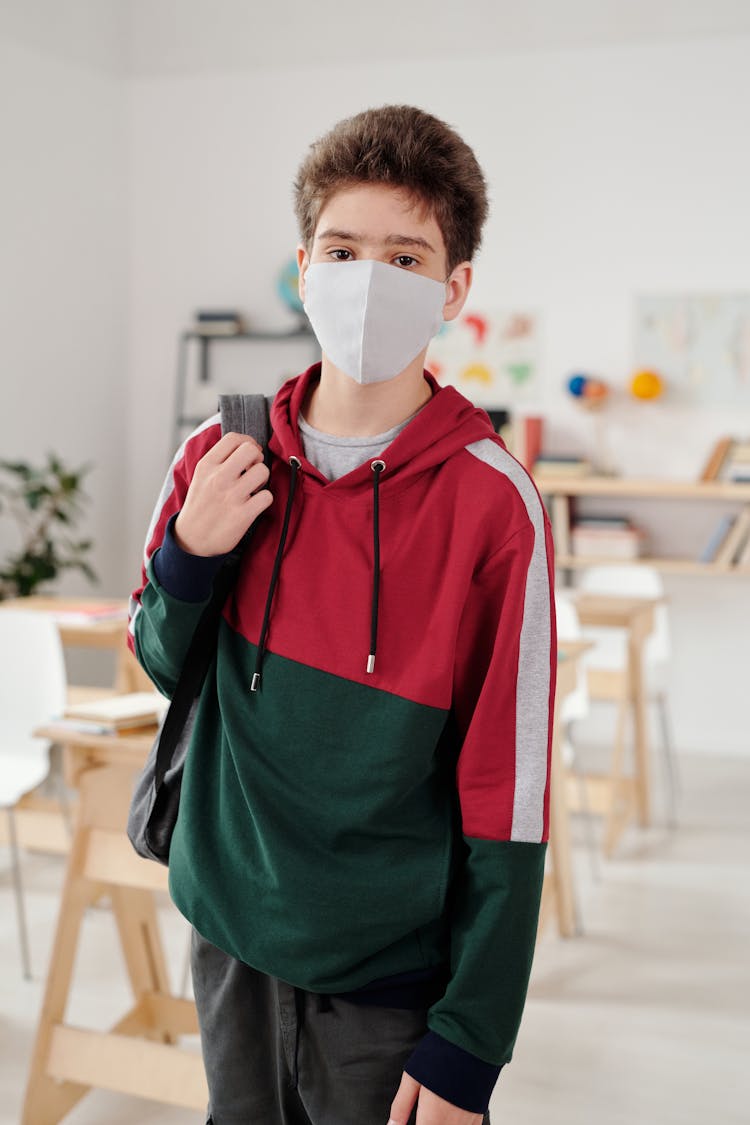 Boy Wearing A Sweater And Facemask Inside A Classroom