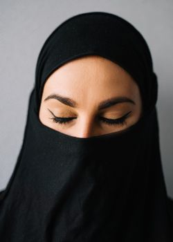 一位戴着头巾、闭着眼睛的女人的特写肖像，展现了优雅的眼线