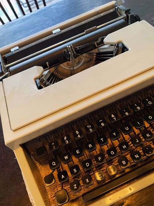 Free Close-up of a vintage typewriter on a wooden table in a cozy setting. Stock Photo