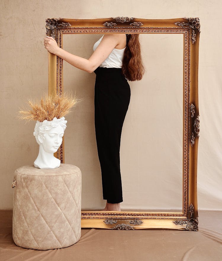 Faceless Stylish Woman Behind Ornamental Frame In Room