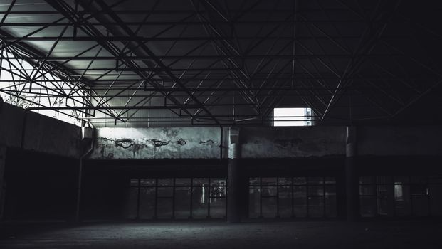 一座废弃工业建筑的内部，钢梁林立，黑暗而空旷