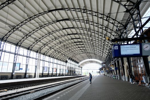 Amsterdam train station interior showing tracks and commuter waiting, captured during the day.