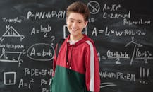 Boy in Red Jacket Standing in Front of the Blackboard