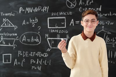 boy proudly shows his maths solution on chalkboard