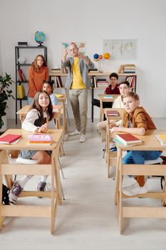 Teacher interacting with diverse group of students in modern classroom setting.