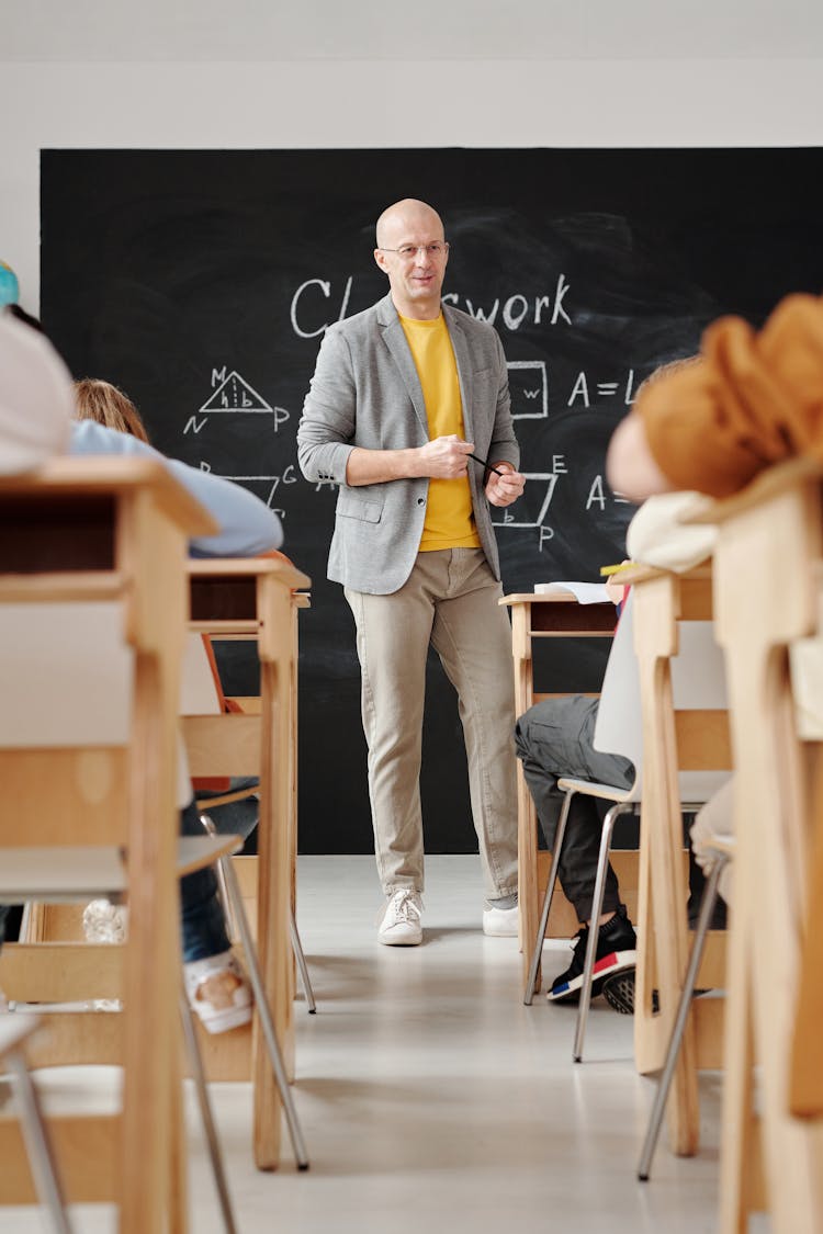 Teacher Standing In Front Of A Blackboard