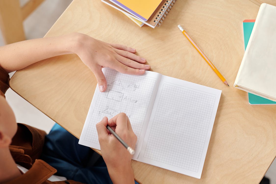 Free A Person Writing on the Notebook Stock Photo