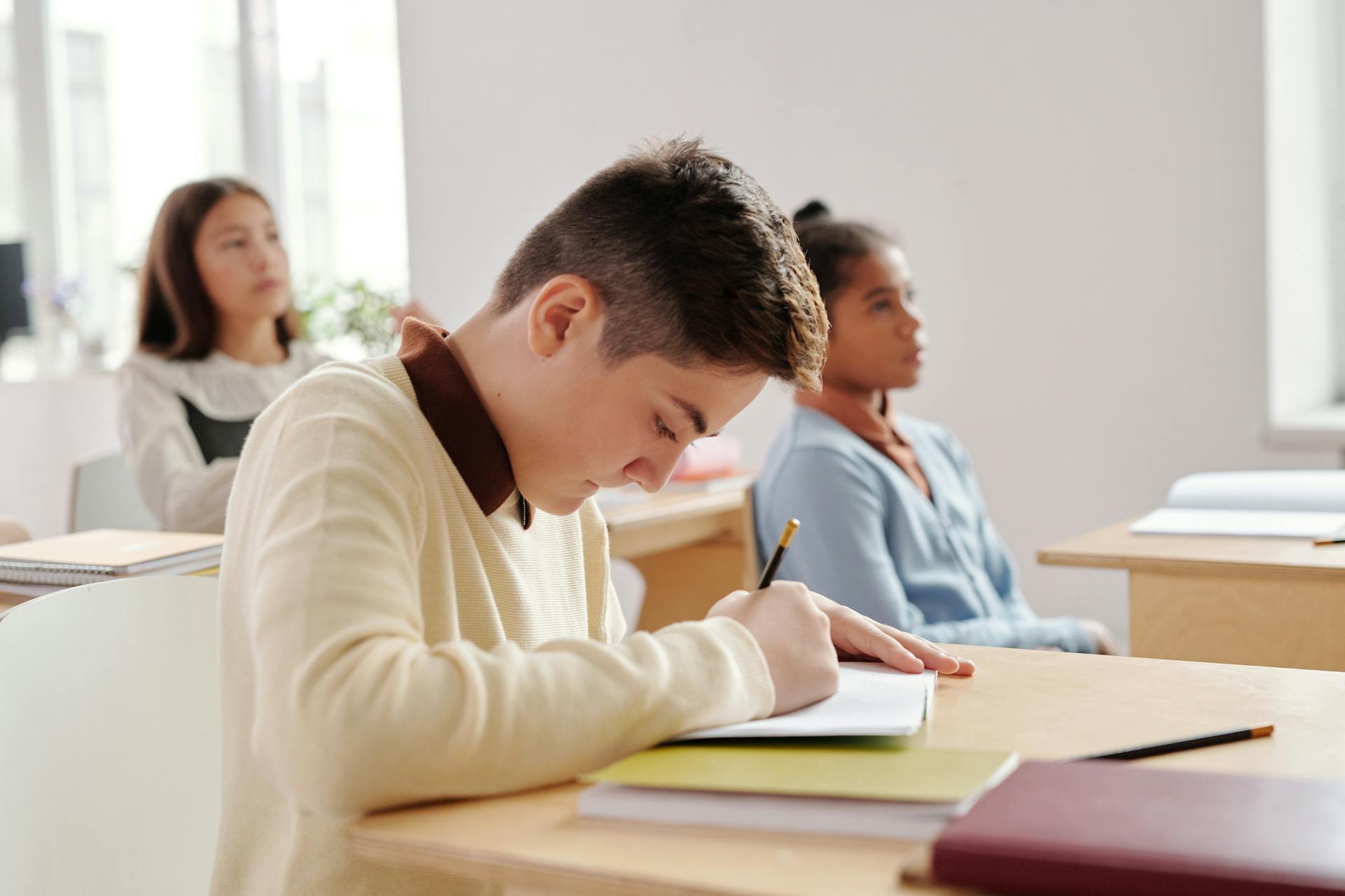 Group of students attentively writing in a classroom setting, focusing on their studies.