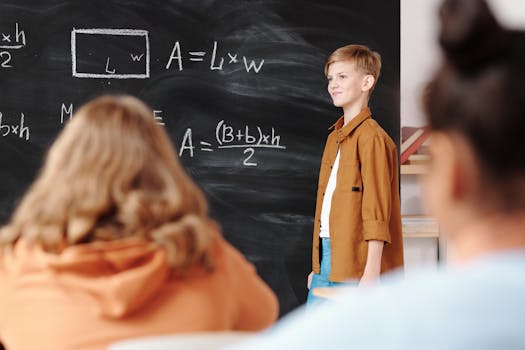 A young student confidently presenting math formulas on a blackboard in a classroom setting.