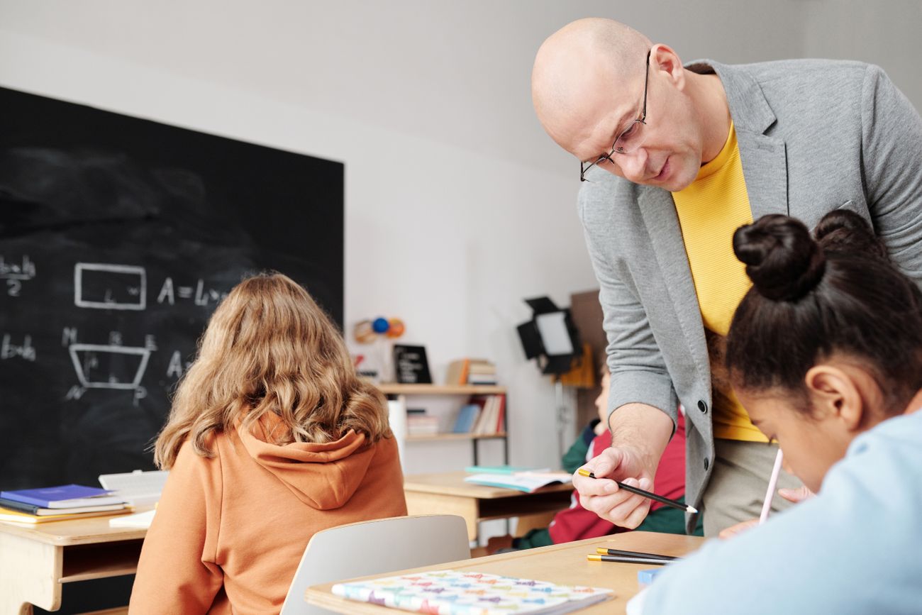 Lehrkraft unterstützt Schülerinnen und Schüler im Unterricht