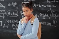 教室里，年轻的学生沉思地摆着姿势，黑板上写着数学方程式