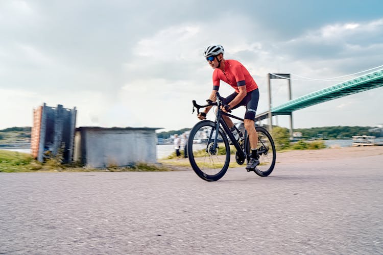 Man In Cyclist Summer Outfit Riding Bicycle In Outskirts 