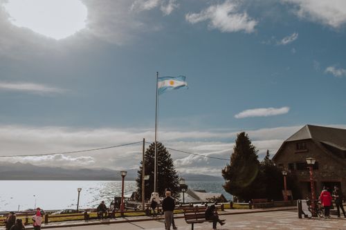 Free Crowded quay with trees and anonymous people on sidewalk near building against cloudy sky above calm sea in sunlight in nature Stock Photo