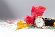 在工作室拍摄的特写中，一块时尚手表旁摆放着充满活力的鲜花和绿植