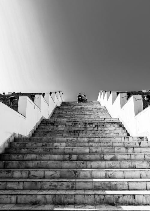 Grayscale Photo of a Couple Sitting on Top of a Stairs