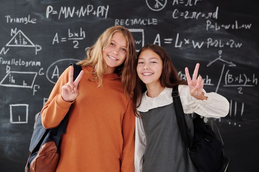 教室里，两个背着背包的学生微笑着站在数学黑板前