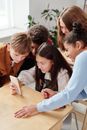 一群青少年在教室里围着智能手机，探索室内技术