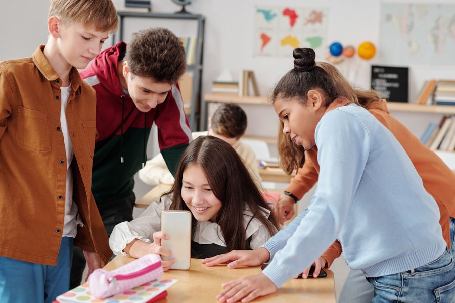 Group of teenagers looking at a smartphone together in a classroom