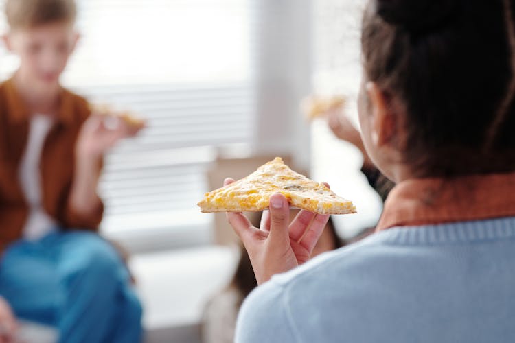 A Child Holding A Pizza 