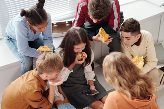 A vibrant scene of teenagers enjoying pizza indoors, capturing the essence of school life.