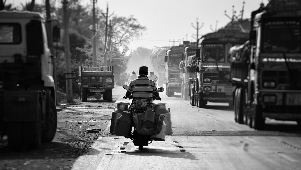 A motorbike riding between trucks