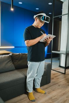 一名成年男子戴着增强现实耳机，在室内用数字平板电脑书写