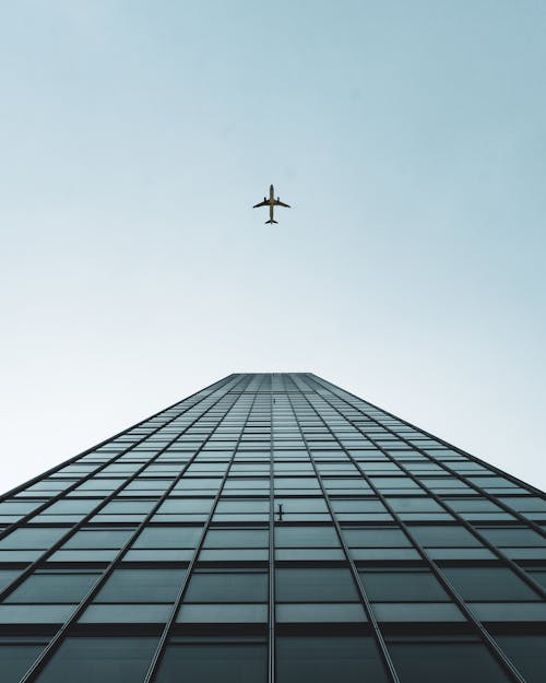 Free An Airplane Flying Over the Tall Building Stock Photo