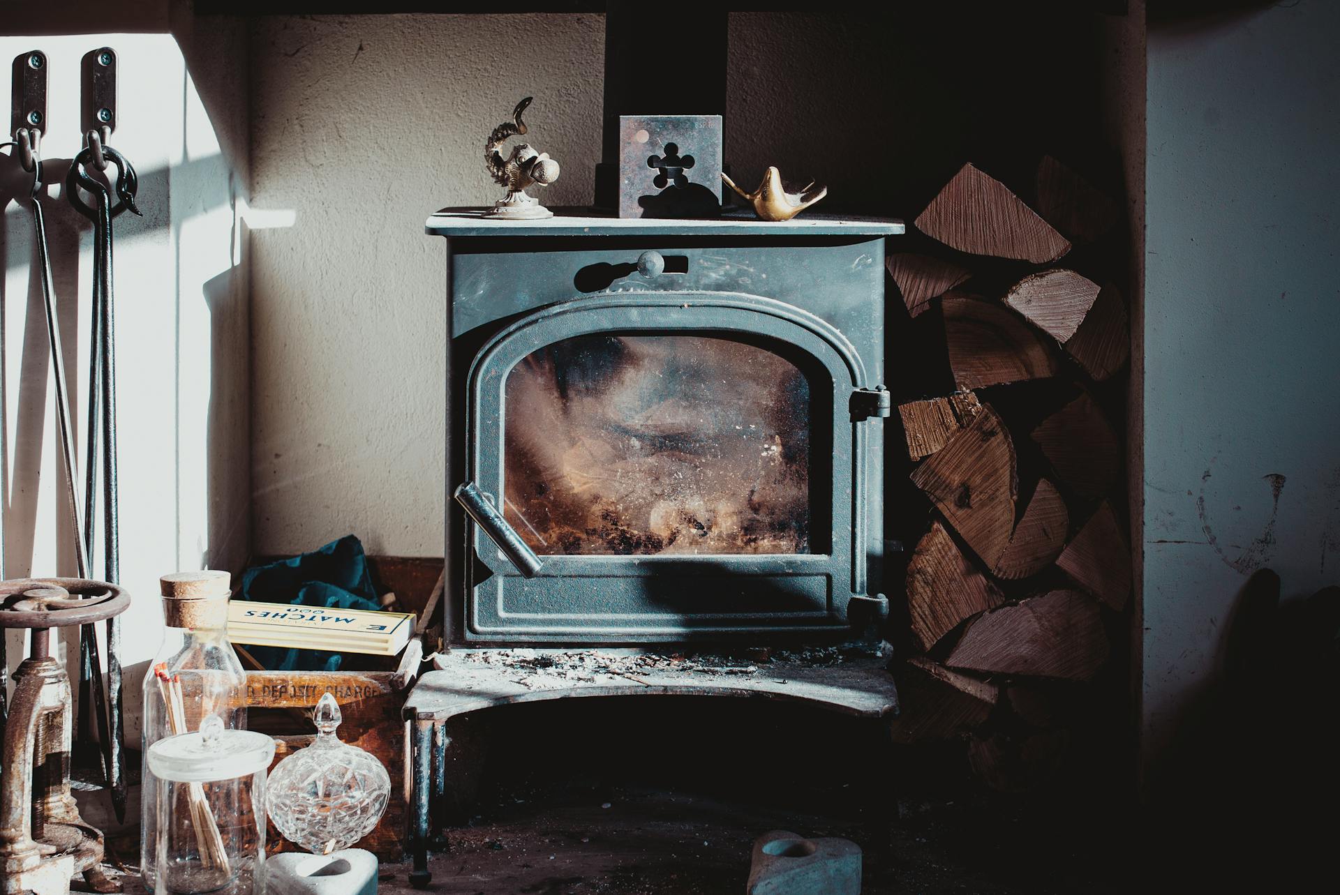 A vintage wood stove with firewood stack in a rustic indoor setting, evoking warmth and nostalgia.
