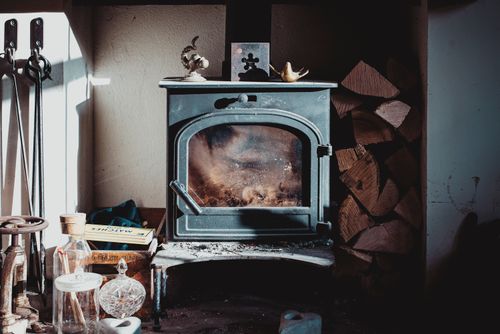 Free Aged vintage fireplace placed on table in rustic house near pile of firewood on sunny day Stock Photo