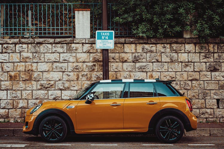 Stylish Compact Orange Car Parked Near Sidewalk In City