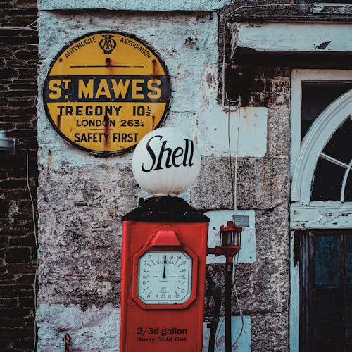 Red retro gas station near entrance of old weathered house