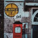 Red retro gas station near entrance of old weathered house