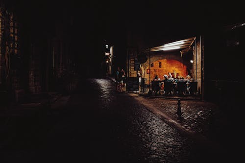 Anonymous travelers resting in cafe in aged town at night