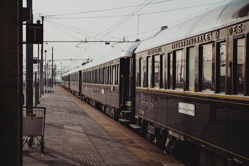 Shiny black aged historical train parked on platform of railway station on sunny day