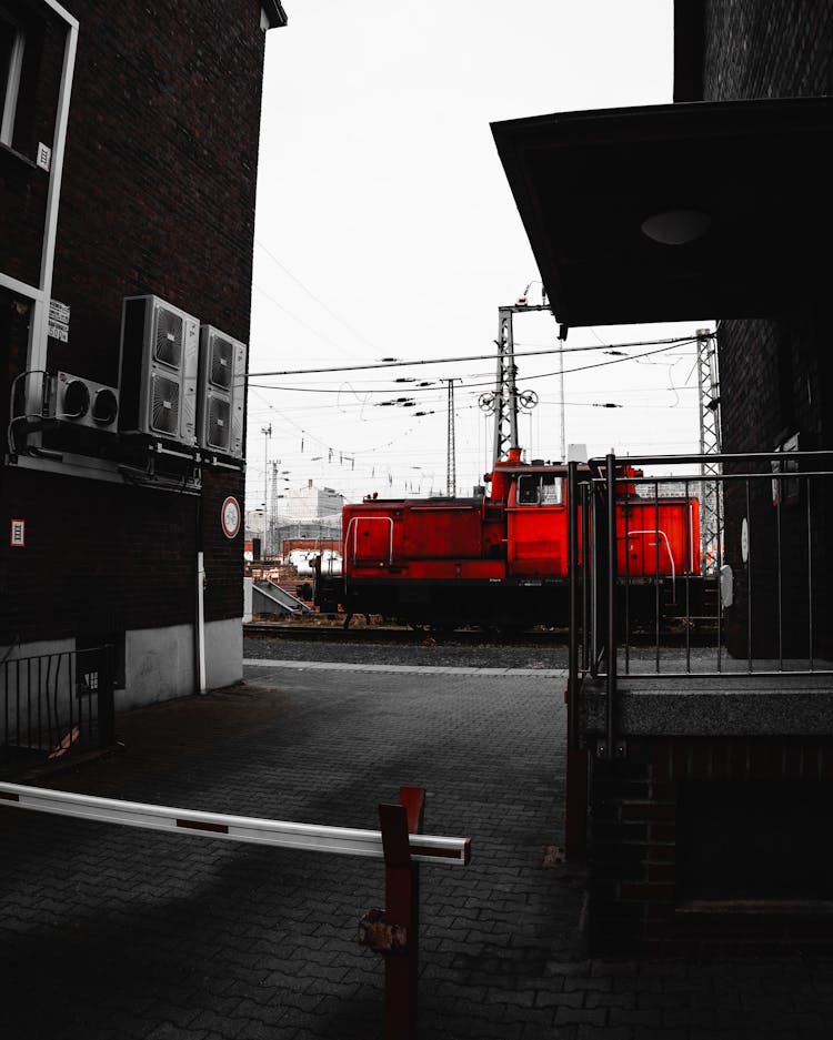 Red Locomotive On Tracks In City Railway