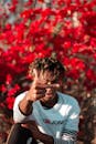 Selective focus of young African American indignant guy showing middle finger while resting in blooming park