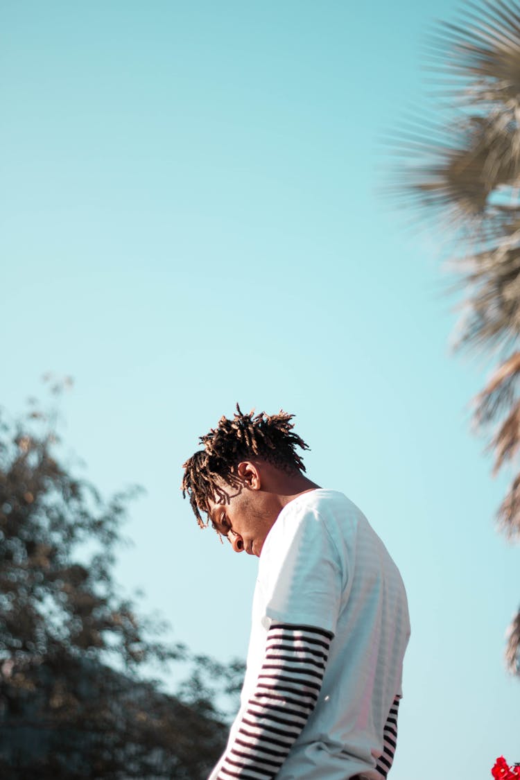 Thoughtful Black Man Standing Against Blue Sky