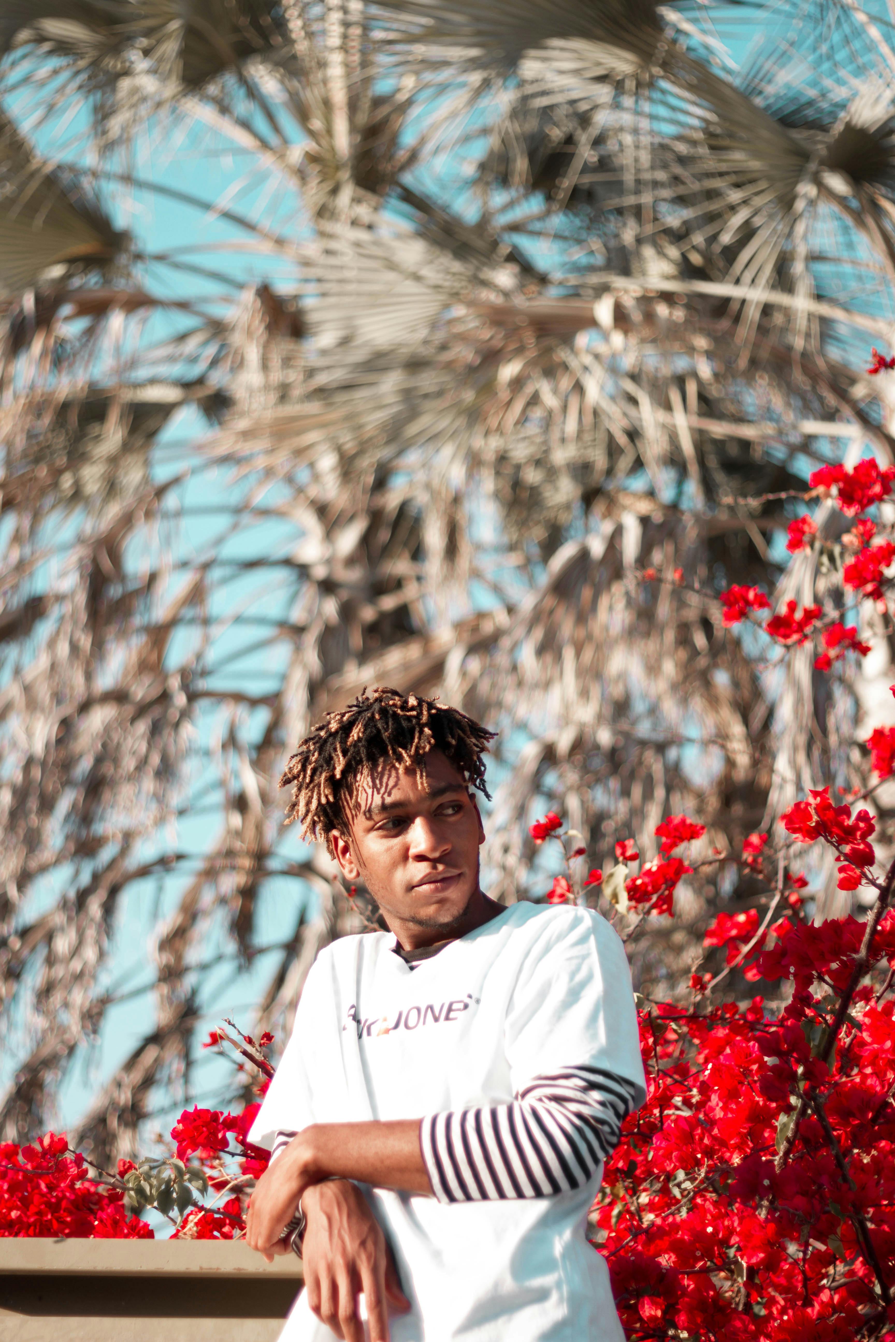 Black confident man standing near lush plants · Free Stock Photo