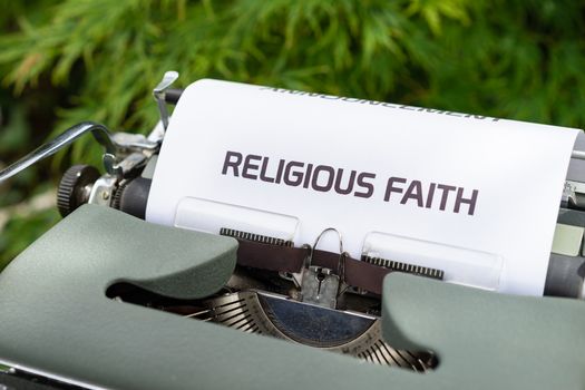 Close-up of a vintage typewriter typing 'Religious Faith' on paper outdoors.