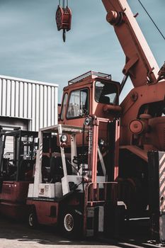 A crane and forklift in an outdoor German industrial zone under a clear sky.