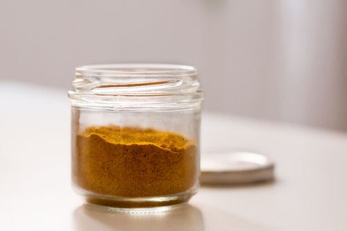 Free Close-up of a glass jar containing aromatic curry powder on a white surface. Stock Photo