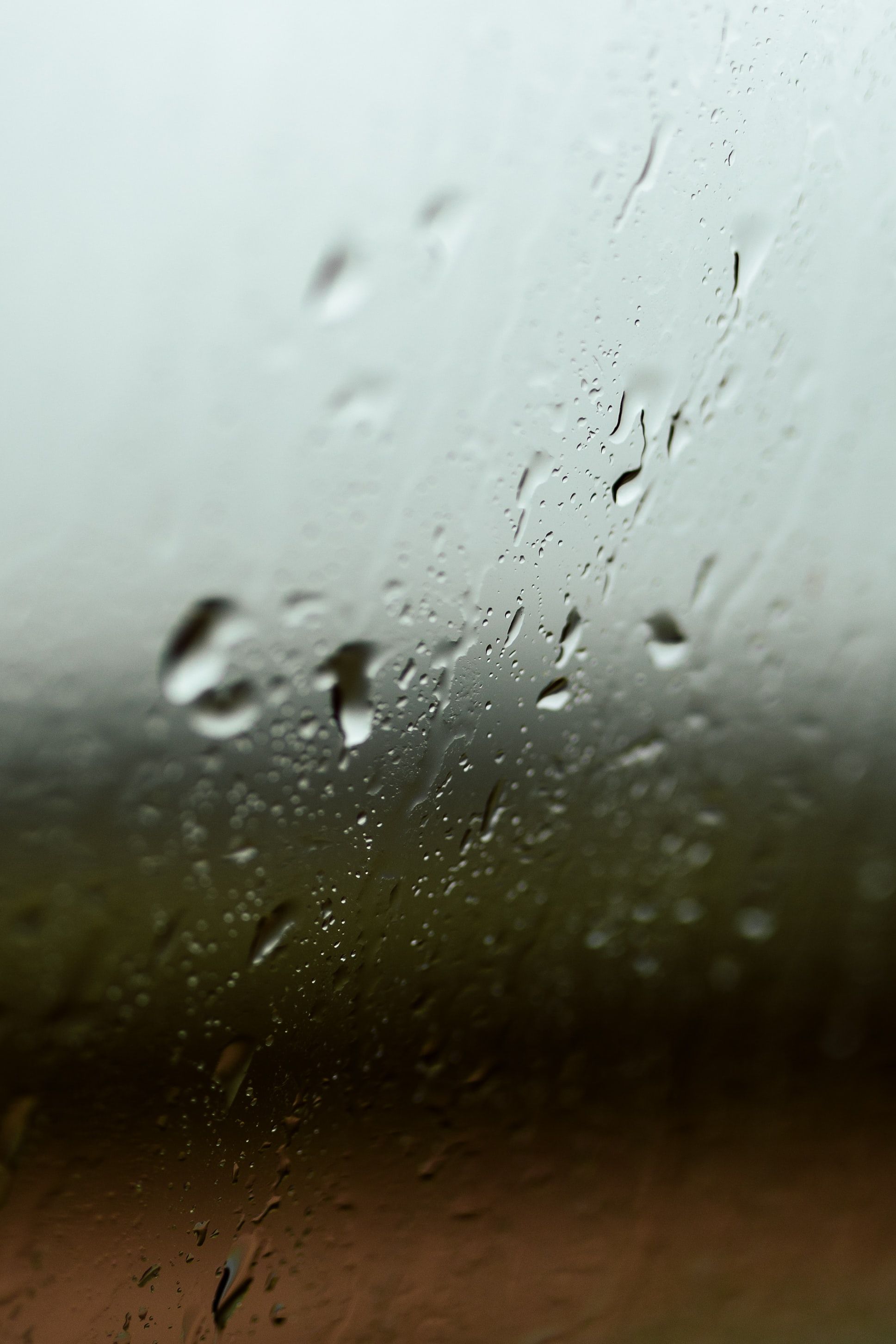 玻璃上雨滴的特写，配上模糊的自然背景，营造出宁静的场景
