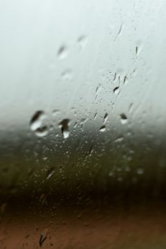 玻璃上雨滴的特写，配上模糊的自然背景，营造出宁静的场景