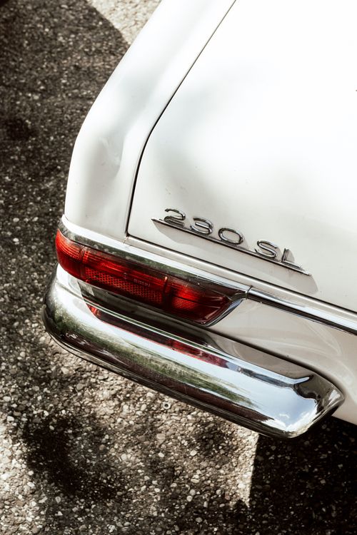 Free From above of white colored retro car with old headlight and shiny bumper on concrete surface on sunny day Stock Photo