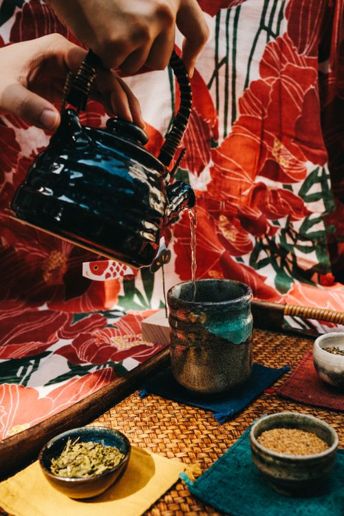 Free Close-up of a Japanese tea ceremony with vibrant floral backdrop and traditional pottery. Stock Photo