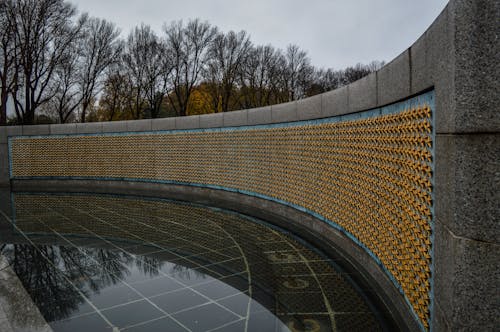 Golden stars on Freedom Wall at World War II Memorial located in in National Mall in Washington DC against gloomy sky