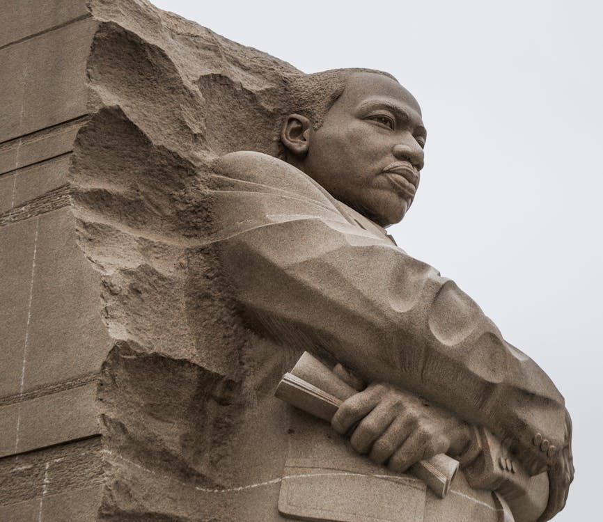 Granite statue of civil rights movement leader against overcast sky