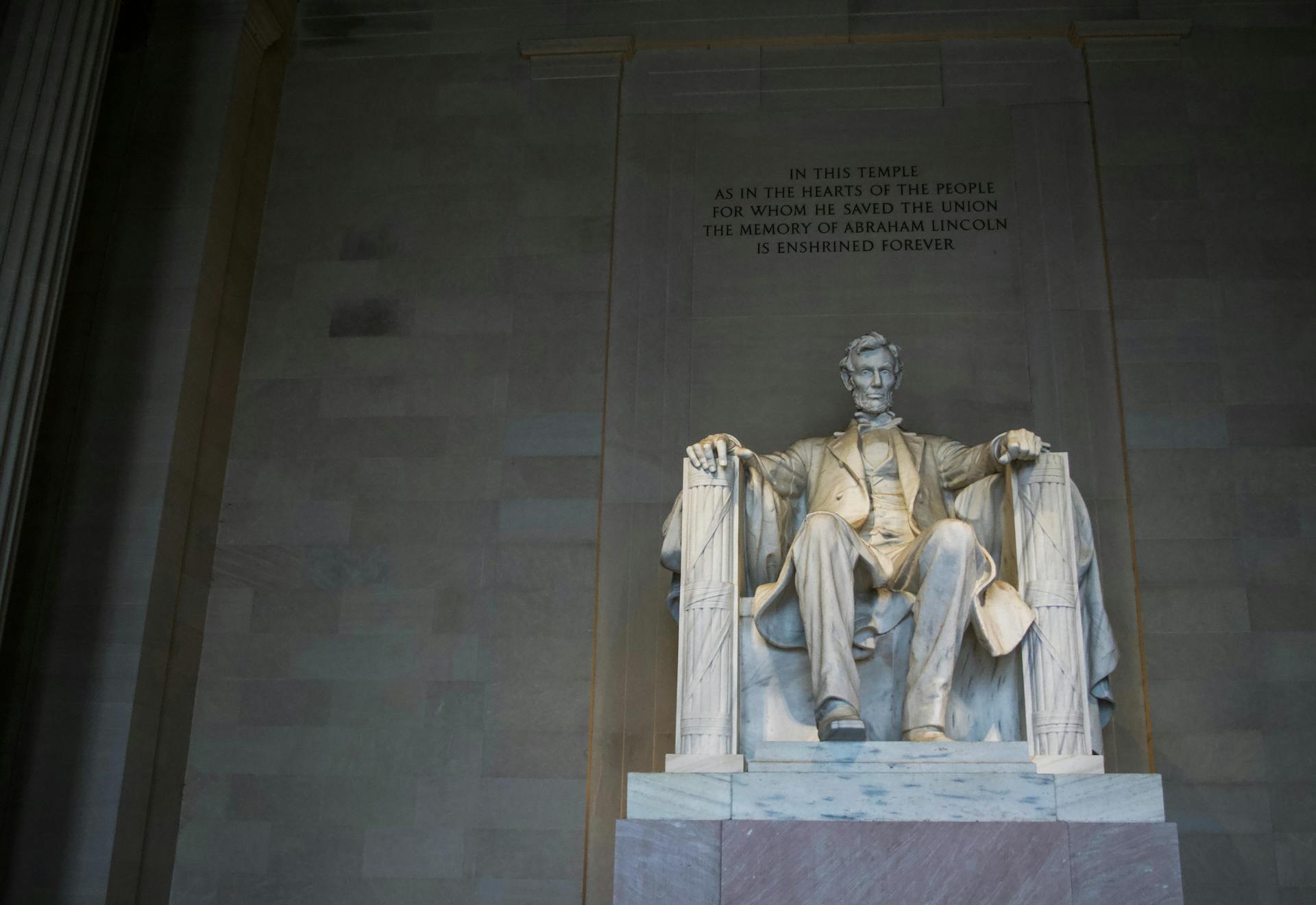 From below of marble statue of American president sitting on chair near wall with inscription located in Washington DC