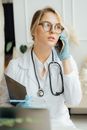 一位穿着白外套、戴着手套的女医生正在医疗办公室里打电话